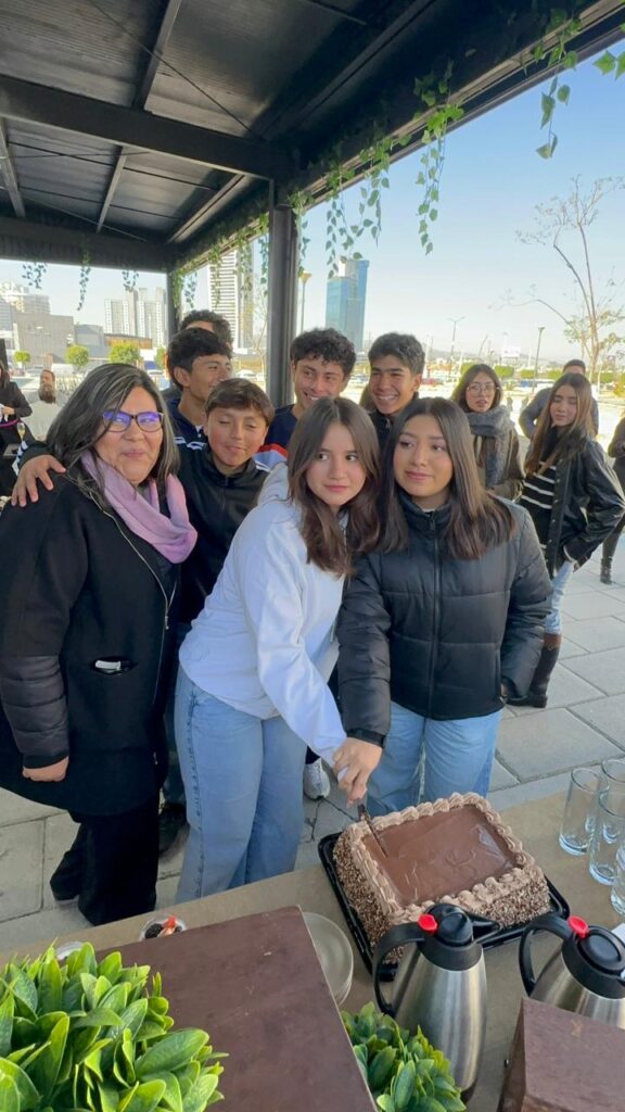 La Maestra Thais Sánchez, directora de Prepa Inter junto a alumnos partiendo el pastel de festejo.